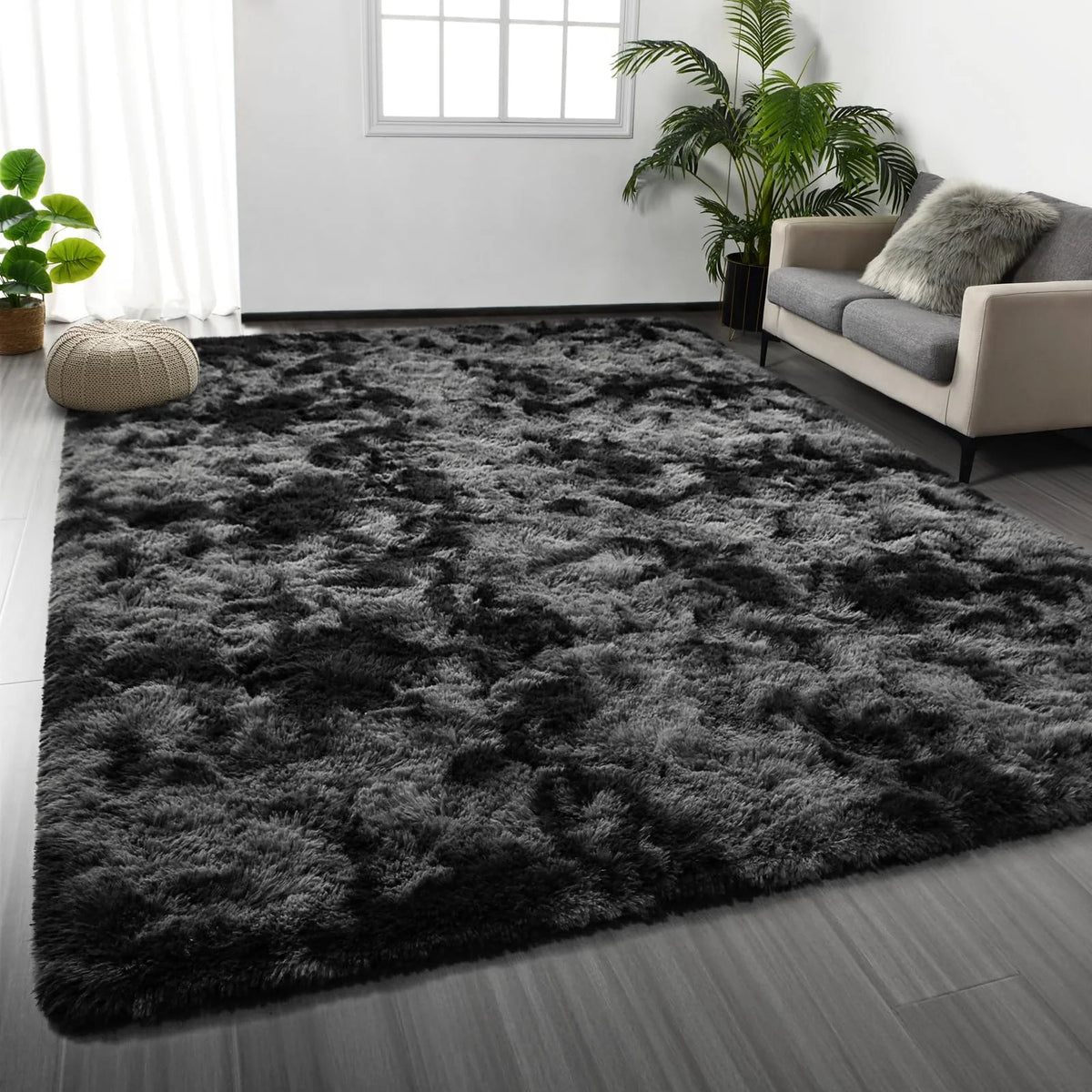 A dark gray shaggy rug with a fluffy texture placed on a wooden floor in a bright room.