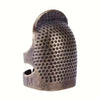 A close-up view of an antique sewing thimble and needle protector set made of dark metal.