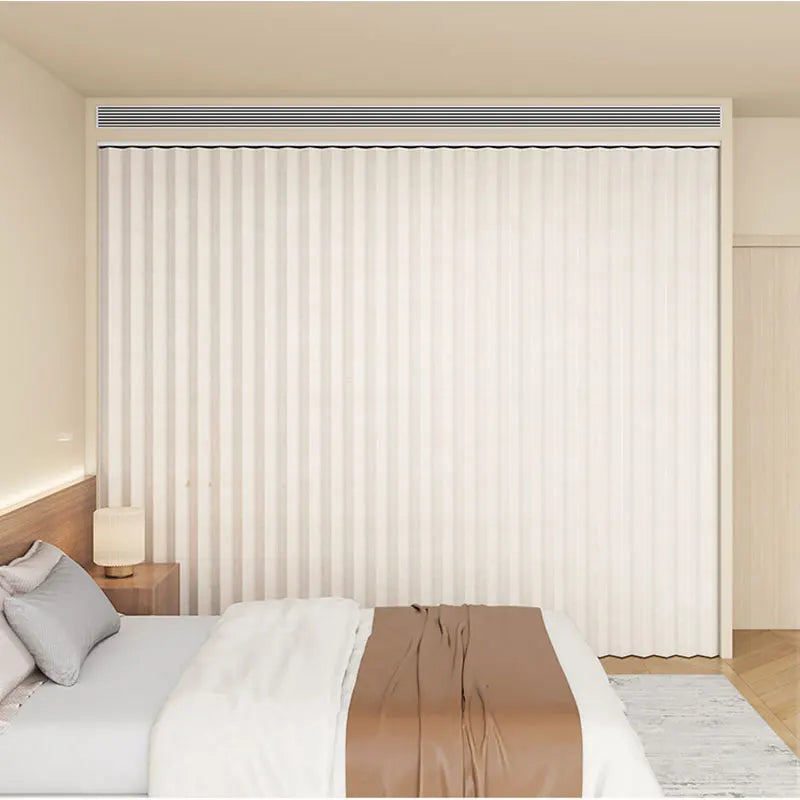 A heavy duty foldable room divider curtain in white with vertical pleats is shown in a bedroom setting.