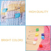 A close-up of stainless steel diaper pins in bright colors with safety locking closures against a white background.