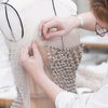 Hands are using precision T-pins to secure fabric on a dress form for crafting and sewing.