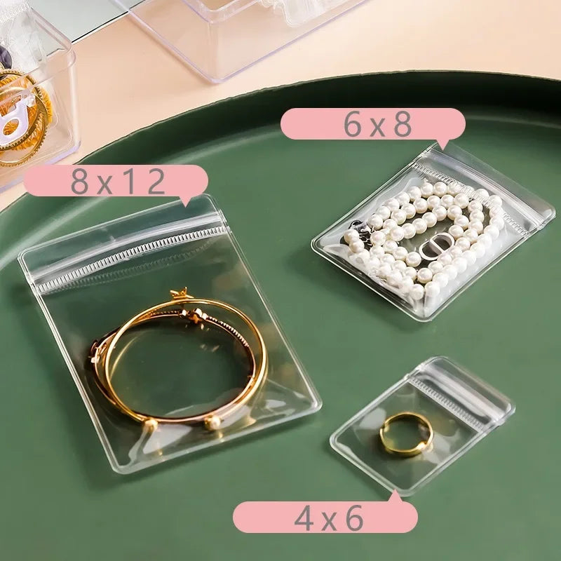 Clear plastic jewelry storage bags with various sizes like 6x8, 8x12, and 4x6 holding gold and silver rings.
