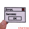 A white embroidered patch featuring text that reads Error, Success!, and OK on a black background.