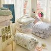 A stack of white and pastel quilted blankets is displayed next to a glass cabinet.