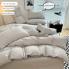 A set of soft gray duvet covers and pillows displayed on a bed with a window in the background.