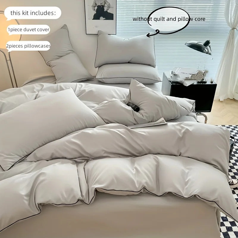 A set of soft gray duvet covers and pillows displayed on a bed with a window in the background.