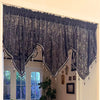 Elegant black lace curtain valance hanging over a window with white trim and glass panes.