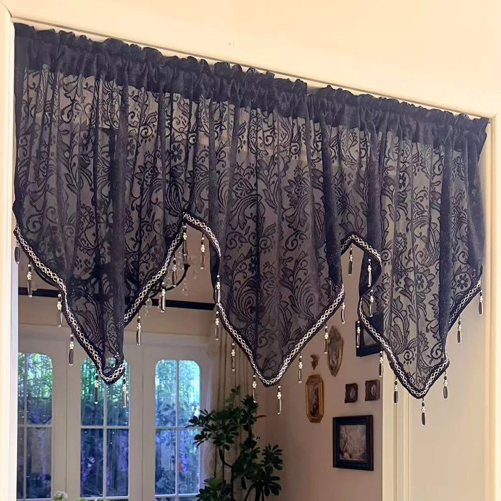 Elegant black lace curtain valance hanging over a window with white trim and glass panes.