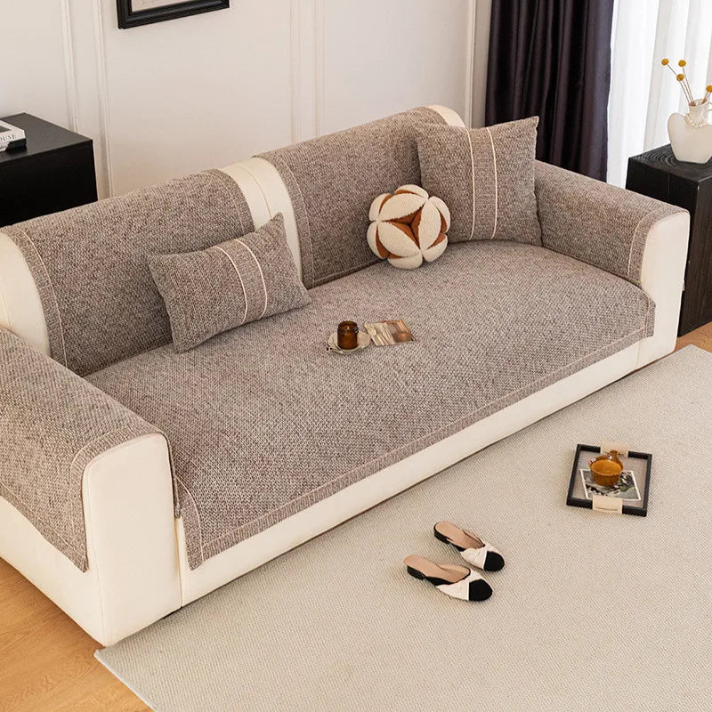 A beige sofa cushion cover with gray fabric and light trim rests on a cream rug.