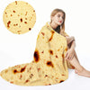 A woman is sitting and wearing a yellow burrito pizza blanket throw.