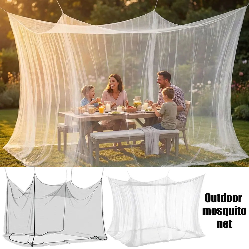 A woman and a man enjoy a meal under a large, sheer white outdoor mosquito net on a grassy lawn.
