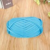 A ball of bright blue flat thread yarn for crafting and sewing lying on a wooden surface.