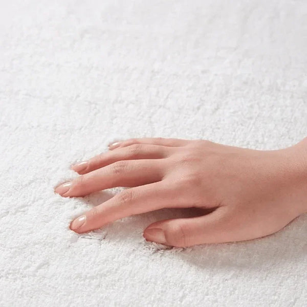 A hand rests on a white fluffy rug, showing skin tone and fingers.