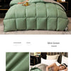A mint green quilted comforter duvet displayed on a bed with dark wood accents and pillows.