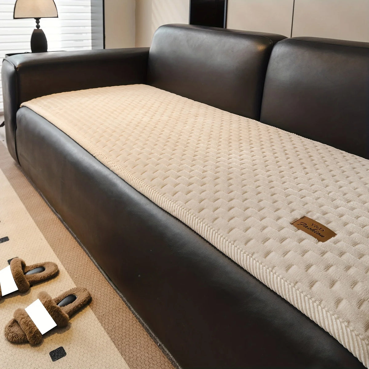 A dark brown leather sofa with a beige quilted cushion and a brown rug.