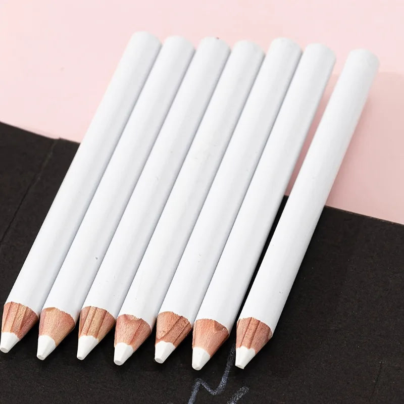 A set of white bamboo chalk pencils with wooden tips arranged diagonally on a black surface.