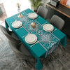 A teal rectangular tablecloth set for dining featuring a white and blue floral pattern with place settings.