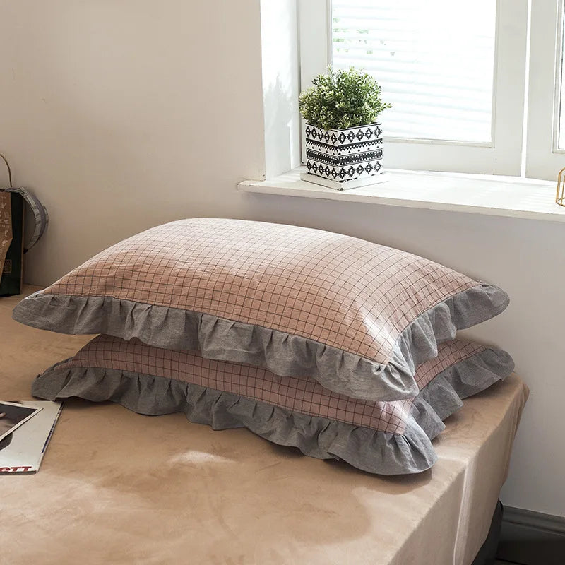 A set of two soft plaid washed cotton pillowcases with ruffled edges displayed on a table.