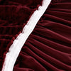 A close-up of a deep burgundy stretch knit sofa cover with white piping and bubble lattice texture.