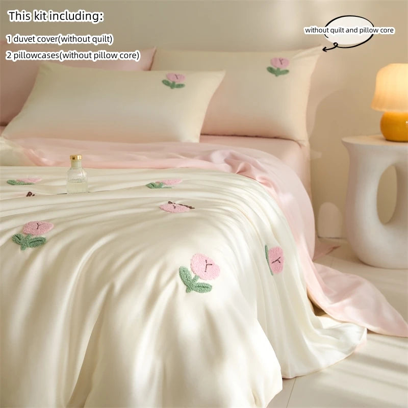 A set of embroidered tulip duvet covers, pillowcases, and a pillow core in soft pink and cream tones.