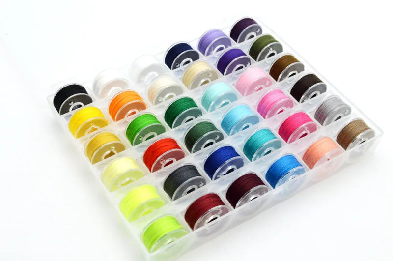A plastic container filled with an assortment of colored sewing thread bobbins.