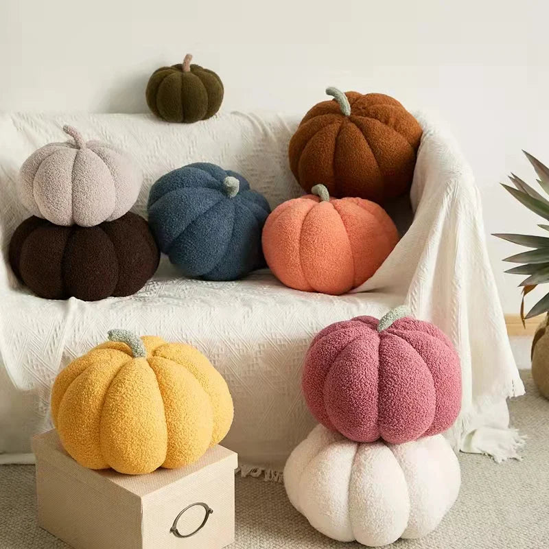 A collection of soft, fuzzy pumpkin plush decorations in various earthy tones like orange, brown, and gray.