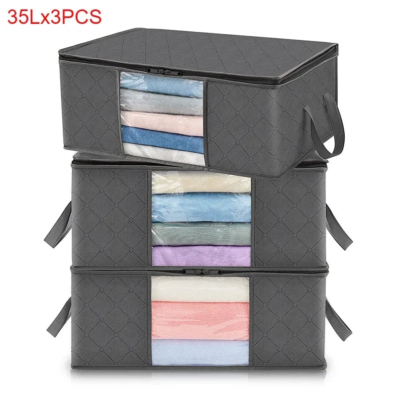 Three stacked gray storage boxes containing folded fabric items like shirts and blankets