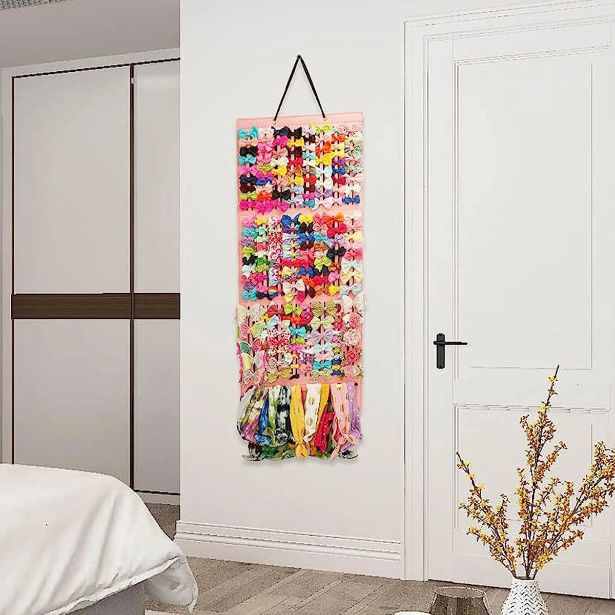 A colorful fabric storage hanger with various hair clips and accessories hanging on a white door.
