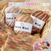 A set of six balls of gradient alpaca wool yarn in various colors and textures displayed in a woven basket.