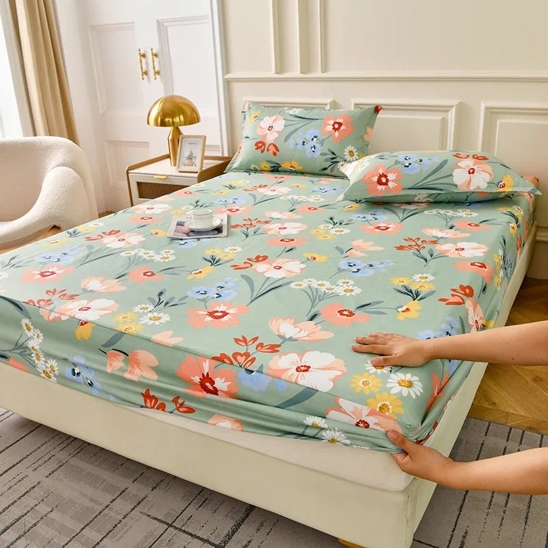 A floral fitted sheet set with green and pink flowers is displayed on a bed with matching pillows.