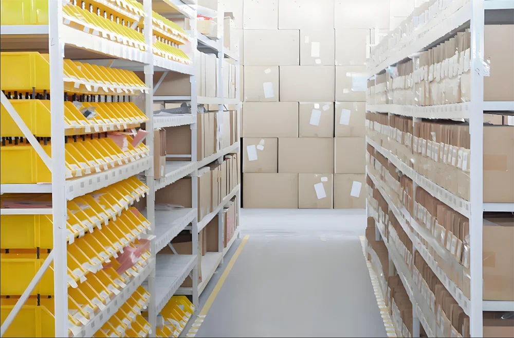 A view inside a warehouse showing rows of yellow and brown precision sewing needles stored in white shelving.