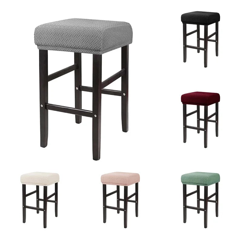 A set of four bar stools with gray, maroon, beige, and green fabric slipcovers.