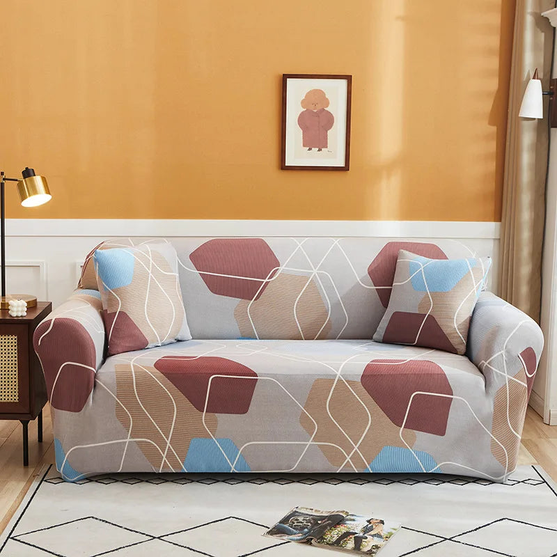 A light gray sofa covered in a patterned slipcover featuring geometric shapes in shades of pink, beige, and blue.