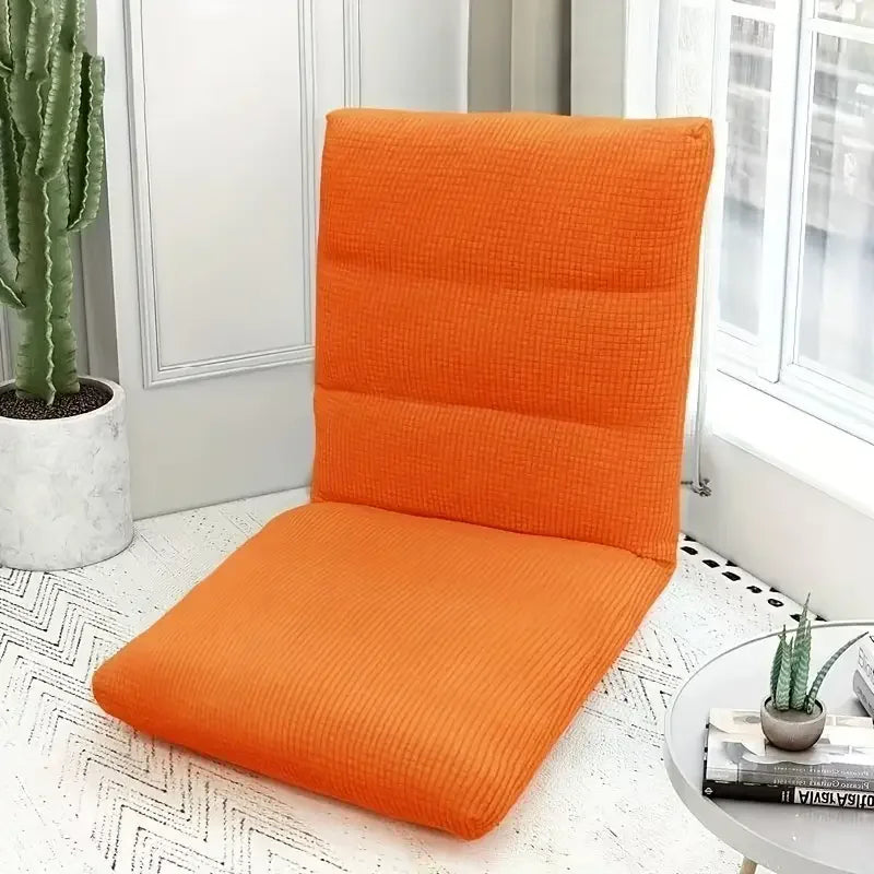 An orange folding tatami seat cover placed on a white floor, next to a potted cactus and a window.