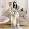 A woman models a long, striped faux fur kimono robe in black and white against a light-colored sofa.