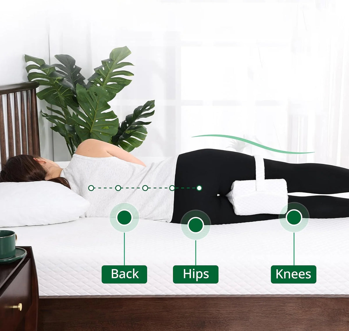 A person lying on a bed demonstrates the placement of a memory foam knee pillow for side sleepers.