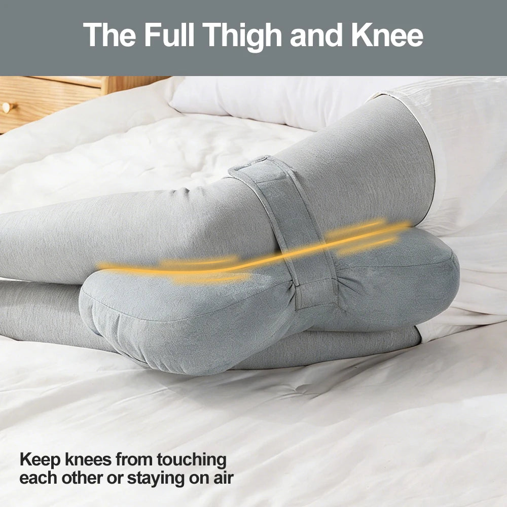 Gray thigh and knee pillow shown resting on white bedding.