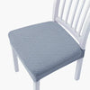 A light blue quilted seat cover for a white wooden bar or dining chair.