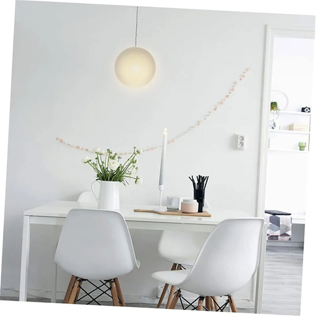 A white modern dining table with two white chairs and a pendant light fixture above it.