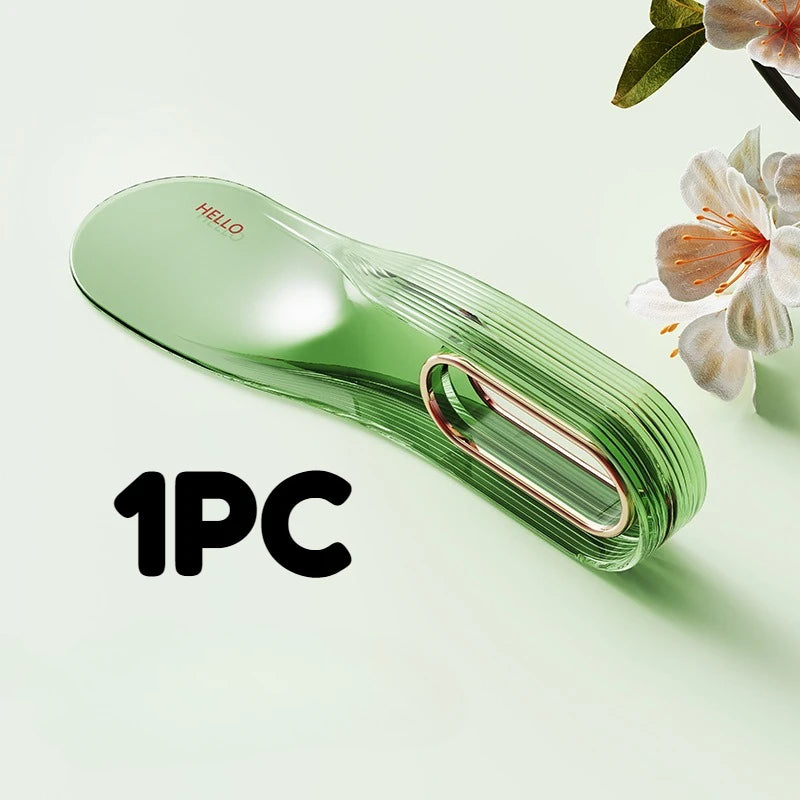 A single piece of clear green plastic mattress lifter and bed linen organizer resting on a light green surface.