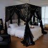 Elegant mosquito net bed canopy with black sheer fabric and warm string lights draped over a white bed.