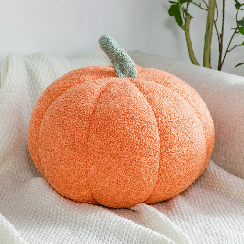 An orange fuzzy pumpkin plush decoration resting on a white textured fabric.
