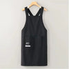 Black water-resistant kitchen apron hanging on a wooden hanger