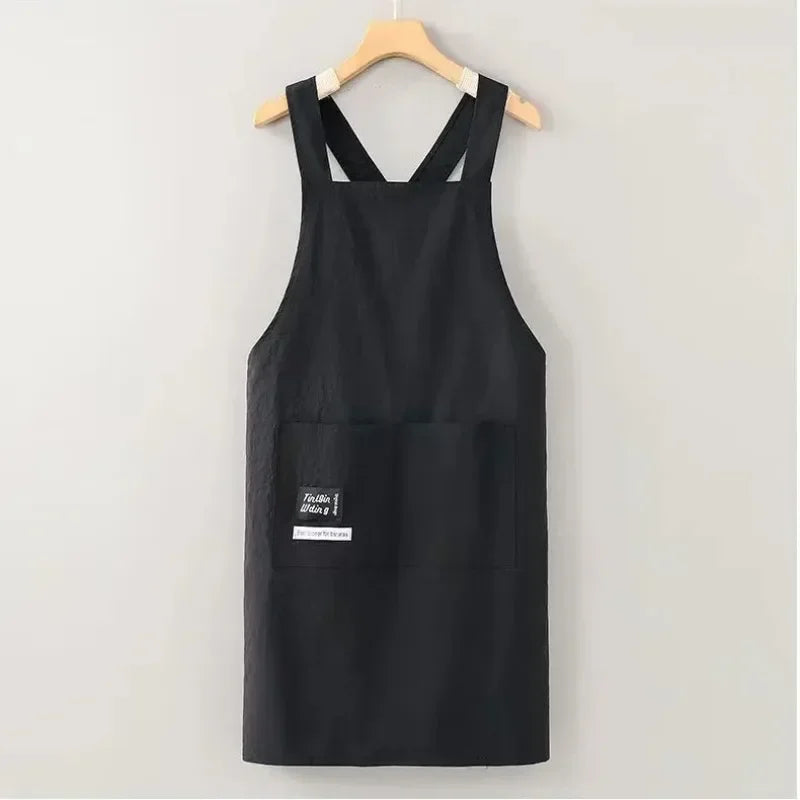 Black water-resistant kitchen apron hanging on a wooden hanger