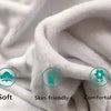 A close-up of a white, soft fleece throw blanket being draped and folded.