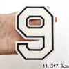 A white and black letter patch shaped like the number 9 is held in a hand.