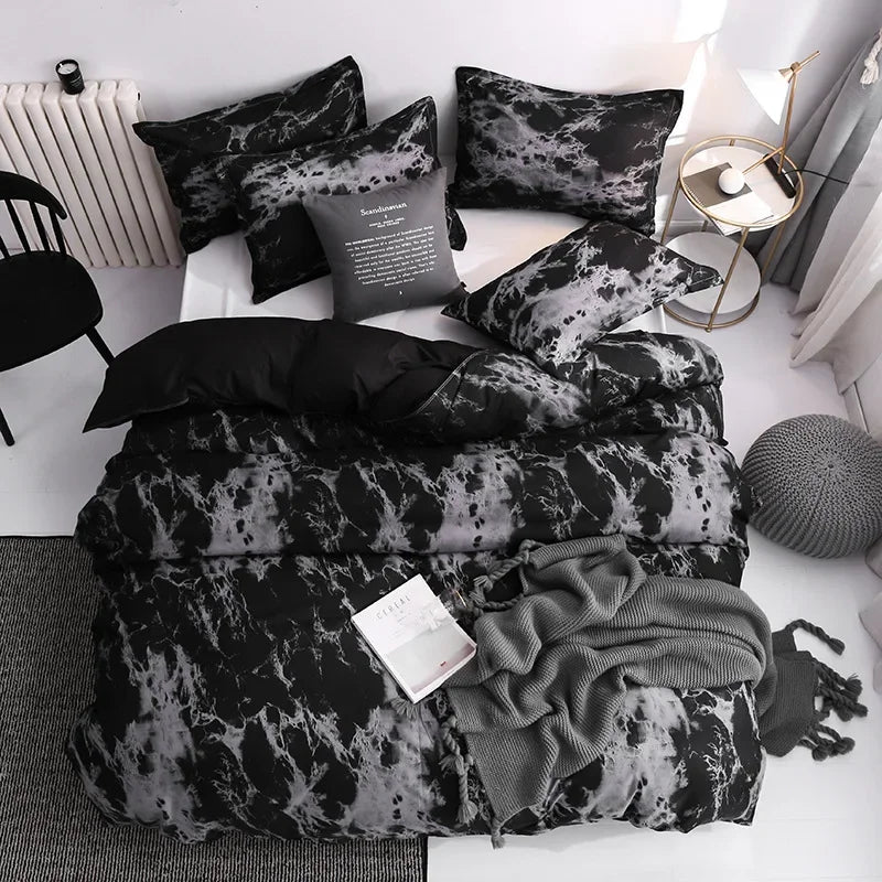 A set of three black and gray tie-dye duvet covers and pillow cases displayed on a white surface.