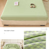 A light green checkered fitted sheet is displayed on a bed, alongside ruffled pillow covers and a folded sheet.