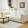 A cream-colored geometric quilted sofa cushion cover displayed on a light-colored sofa in a bright room.