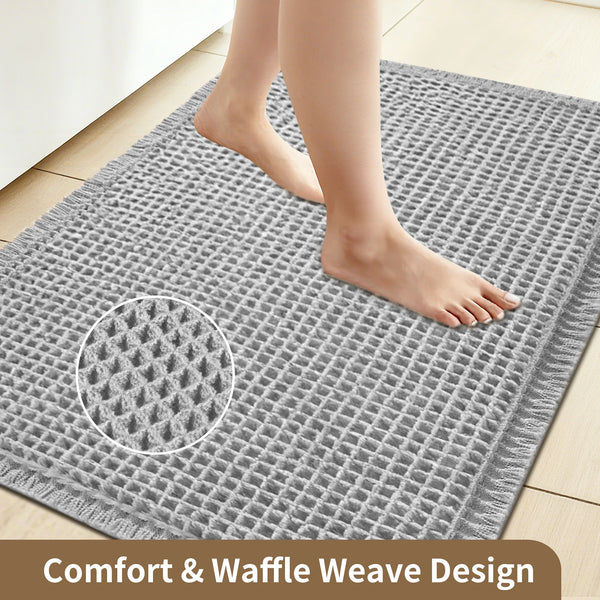 A gray waffle weave bathroom mat with a foot resting on it, showing the comfort and waffle weave design.
